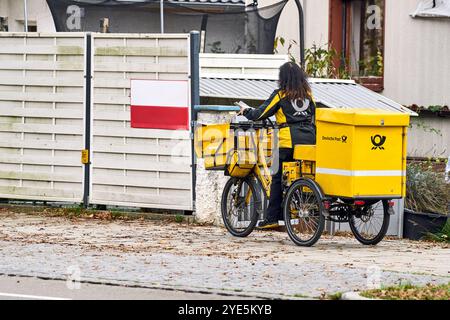 Gersthofen, Bayern, Deutschland - 29. Oktober 2024: Eine Postpostfrau der Deutschen Post bei der Zustellung von Briefen mit dem Fahrrad *** eine Postbotin der Deutschen Post bei der Zustellung von Briefen mit dem Fahrrad Stockfoto