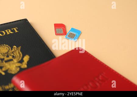 Moderne SIM-Karten und Pass auf beigefarbenem Hintergrund, Nahaufnahme Stockfoto