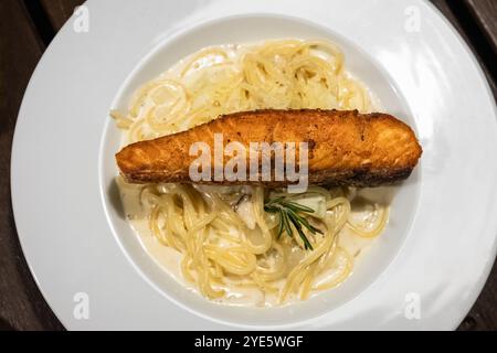 Italienische Küche Spaghetti mit Lachs- und Frischkäsesauce, Nahaufnahme auf dem Teller auf dem Tisch. Hausgemachtes Gericht aus Lachs mit Spaghetti auf einem Teller. Eine Platte Stockfoto