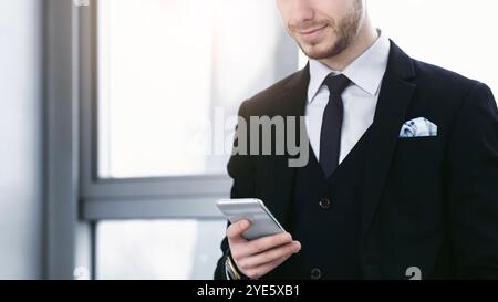 Lächelnder Mann hält und schaut auf das Telefon Stockfoto