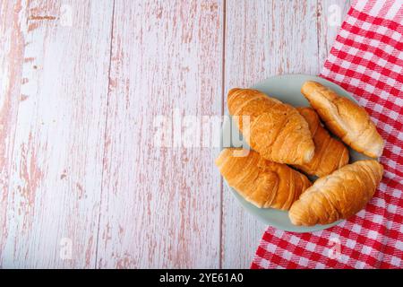 Buttercroissants ruhen auf einem hellen Holztisch, von oben betrachtet. Die einfache Einstellung hebt die goldene Textur der Backwaren auf der Natur hervor Stockfoto