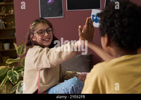 Zwei Freunde, die in gemütlicher Atmosphäre aufgeregt und glücklich aussehen. Umgeben von Pflanzen und Wanddekor, die fröhliche Interaktion und Freundschaft im Innenbereich zeigen Stockfoto