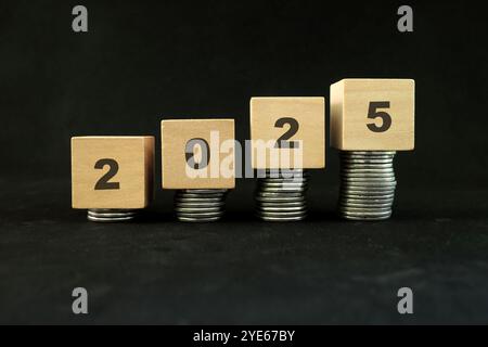 Geschäftskonzept „Geldanlage investieren und wachsen“ im Jahr 2025. Immer mehr Münzen in Holzblöcken. Stockfoto