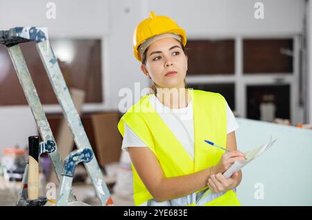 Konzentrierte weibliche Sicherheitsinspektorin macht Notizen auf der Baustelle Stockfoto