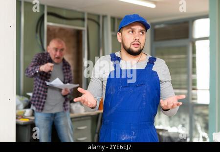 Der Reparaturmann wurde von einem wütenden Besitzer der Wohnung verwirrt Stockfoto