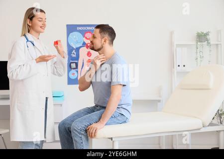 Endokrinologin zeigt Schilddrüsenmodell beim Mann in der Klinik Stockfoto