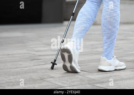 Sportliche Frau, die Nordic Walking auf der Straße macht, Rückansicht Stockfoto