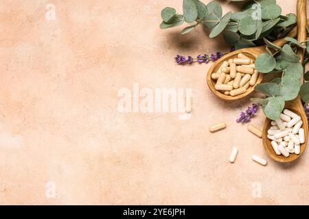 Holzlöffel mit Pillen und Eukalyptuszweig auf farbigem Hintergrund Stockfoto