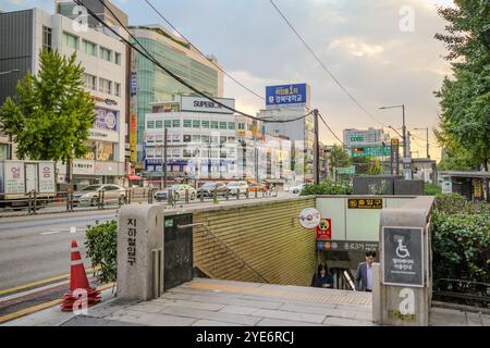 Der Mann läuft einen U-Bahn-Eingang entlang. Das Schild ist in einer fremden Sprache. Es gibt viele Autos auf der Straße Stockfoto