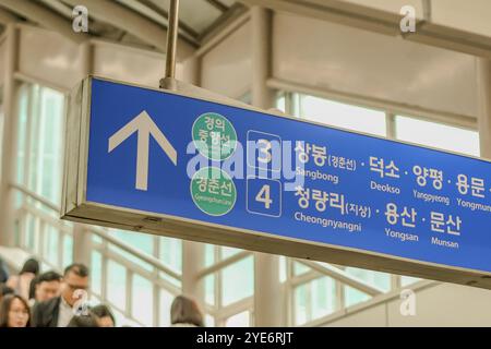 Blaues Schild mit einem weißen Pfeil nach oben. Das Schild ist in einer fremden Sprache. Mehrere Leute laufen am Schild vorbei Stockfoto
