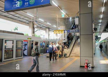 Eine Gruppe von Leuten läuft die Treppe an einem Bahnhof hoch. Im Hintergrund befinden sich mehrere Schilder Stockfoto