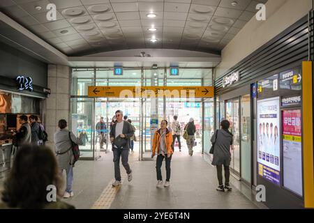 Eine Gruppe von Menschen läuft durch einen Bahnhof. Es gibt Schilder an der Wand, auf denen 7 und 4 steht Stockfoto