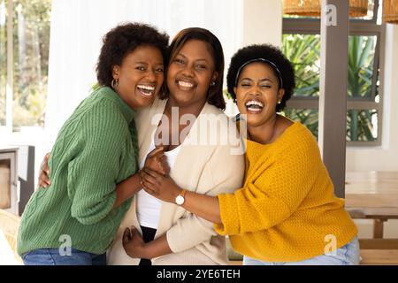 Gemeinsam lachen, fröhliche afroamerikanische Freundinnen, die sich in gemütlicher Atmosphäre umarmen Stockfoto