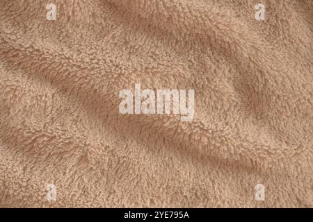 Beige zart weicher Hintergrund aus Plüschstoff. Textur aus weichem Kunstpelzgewebe mit schönen Falten, Nahaufnahme, hohe Auflösung. Stockfoto