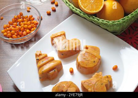 Gefrorener Sanddorn- und Orangentee in Weihnachtsformen auf weißem Teller in der Küche. Gesunde Ernährung und Jahreszeiten. Stockfoto