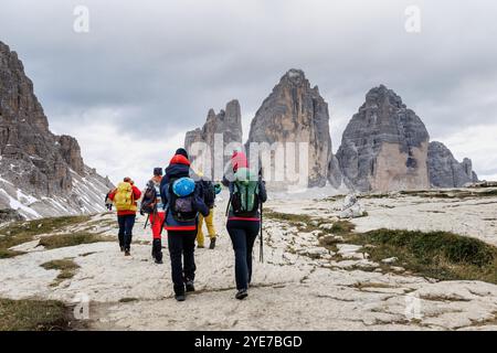 18. September 2024, Italien, Auronzo Di Cadore: Wanderer mit Wanderausrüstung, Kletterausrüstung mit Helm und Wanderrucksack spazieren am 18. September 2024 auf einem Wanderweg vor dem Panorama der Nordwände der drei Zinnen in den Sexten-Dolomiten im Naturpark drei Zinnen bei Auronzo di Cadore (Provinz Belluno, Italien). Die drei Zinnen (italienisch Tre Cime di Lavaredo) sind ein markantes Bergmassiv in der Berglandschaft an der Grenze zwischen den italienischen Provinzen Belluno im Süden und Südtirol im Norden und ein Symbol der Region. Die Dolomiten sind die h Stockfoto