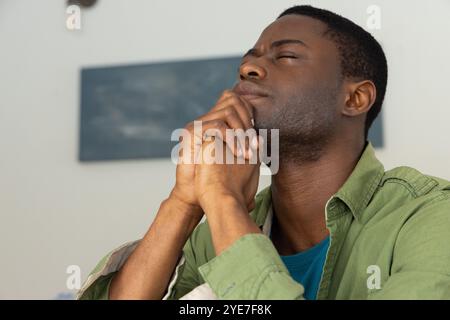 Afroamerikaner zu Hause, reflektiert mit geschlossenen Augen, fühlt sich friedlich Stockfoto