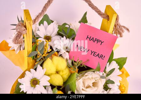 Das Konzept des Urlaubs. Der konzeptionelle Glückwunschtext, Satz, Ausdruck HAPPY NEW YEAR ist eine rote Karte in einem Blumenstrauß geschrieben. Stockfoto