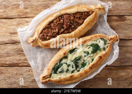 Traditionelles türkisches Backgericht Pide mit Hackfleisch, Käse, Spinat und scharfer Nahaufnahme auf Holzbrett auf dem Tisch. Horizontale Draufsicht von oben Stockfoto