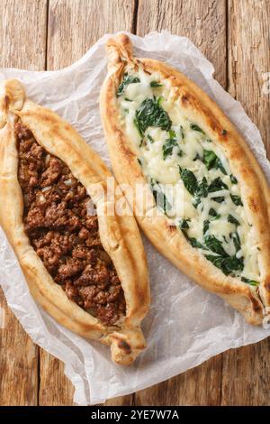 PIDE ist ein türkisches pizzaähnliches Gericht, das aus einem bootförmigen Fladenbrot mit Füllung auf einem Holztisch hergestellt wird. Vertikale Draufsicht von oben Stockfoto