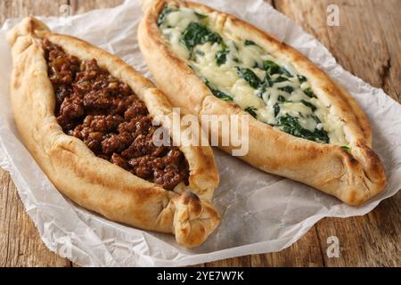 Traditionelles türkisches Backgericht Pide mit Hackfleisch, Käse, Spinat und scharfer Nahaufnahme auf Holzbrett auf dem Tisch. Horizontal Stockfoto