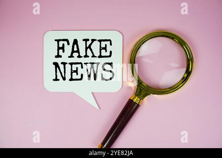 Fake News Text auf Sprechblase mit Lupe oben auf rosa Hintergrund Stockfoto