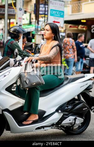 Eine junge Thai-Dame macht sich auf ihrem Roller auf dem Weg entlang Soi Buakhao Pattaya, Thailand. Stockfoto