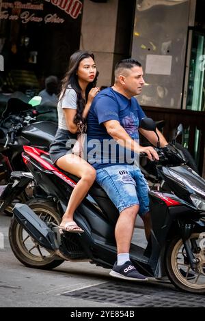 Ein westlicher Mann macht sich auf den Weg durch Soi Buakhao, Pattaya Thailand, mit einer jungen thai-Dame auf der Rückseite des Rollers oder Fahrrads. Stockfoto