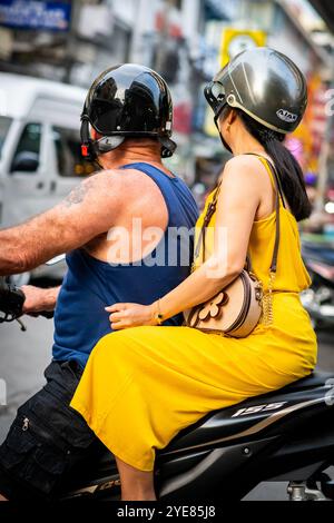 Ein westlicher Mann macht sich auf den Weg durch Soi Buakhao, Pattaya Thailand, mit einer jungen thai-Dame auf der Rückseite des Rollers oder Fahrrads. Stockfoto