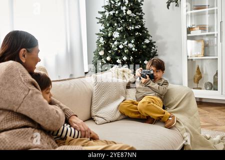 Ein fröhlicher Junge, der Fotos von der Familie macht, genießt schöne Zeit am Weihnachtsbaum Stockfoto