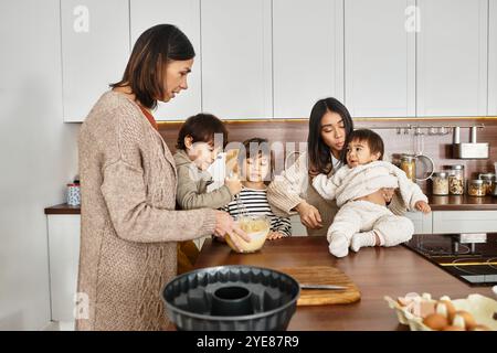 Eine fröhliche Familie versammelt sich in einer modernen Küche und genießt in diesem Winter Backaktivitäten mit ihren kleinen Kindern. Stockfoto