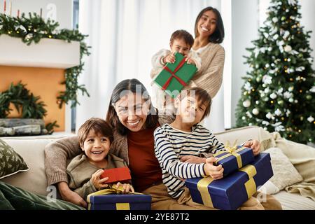 Eine fröhliche Familie versammelt sich am Weihnachtsbaum, teilt Geschenke und lacht in ihrem modernen Winterurlaub. Stockfoto