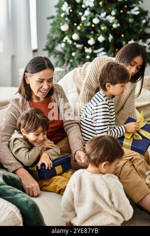 Eine fröhliche Familie versammelt sich in einem modernen Wohnzimmer, wo sie während der Weihnachtszeit lacht und Geschenke teilt. Stockfoto