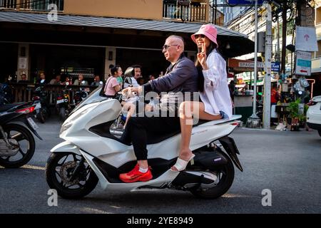 Ein westlicher Mann macht sich auf den Weg durch Soi Buakhao, Pattaya Thailand, mit einer jungen thai-Dame auf der Rückseite des Rollers oder Fahrrads. Stockfoto