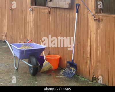 Eine Schubkarre und Werkzeuge, um einen Pferdestall auszumustern. Stockfoto
