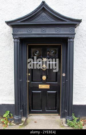 Stilvolle Eingangstür in einer Marktstadt in Suffolk, frisch lackiert in glänzendem Schwarz und mit Messingbeschlägen einschließlich Türklopfer, Briefkasten und 38. Stockfoto