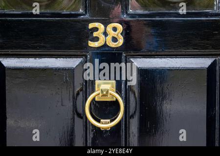 Stilvolle Eingangstür in einer Marktstadt in Suffolk, frisch lackiert in glänzendem Schwarz und mit Messingbeschlägen einschließlich Türklopfer, Briefkasten und 38. Stockfoto