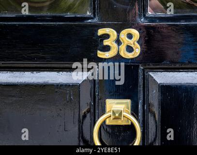 Stilvolle Eingangstür in einer Marktstadt in Suffolk, frisch lackiert in glänzendem Schwarz und mit Messingbeschlägen einschließlich Türklopfer, Briefkasten und 38. Stockfoto