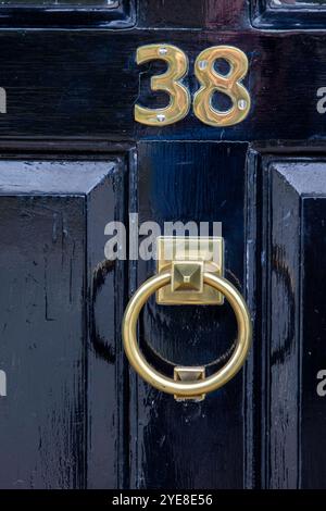 Stilvolle Eingangstür in einer Marktstadt in Suffolk, frisch lackiert in glänzendem Schwarz und mit Messingbeschlägen einschließlich Türklopfer, Briefkasten und 38. Stockfoto