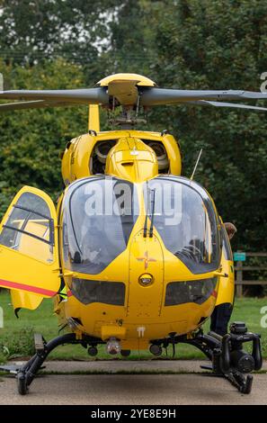 Der leuchtend gelbe Ambulanzwagen East Anglian Air, der auf einen Notfall im ländlichen Framlingham Suffolk reagiert hat, wartet mit der Besatzung auf einem Parkplatz Stockfoto