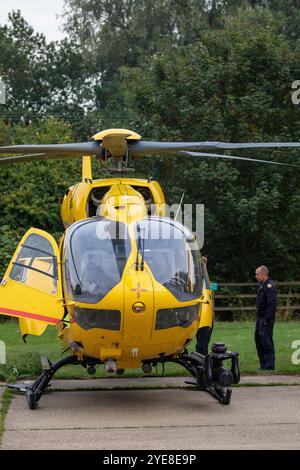 Der leuchtend gelbe Ambulanzwagen East Anglian Air, der auf einen Notfall im ländlichen Framlingham Suffolk reagiert hat, wartet mit der Besatzung auf einem Parkplatz Stockfoto