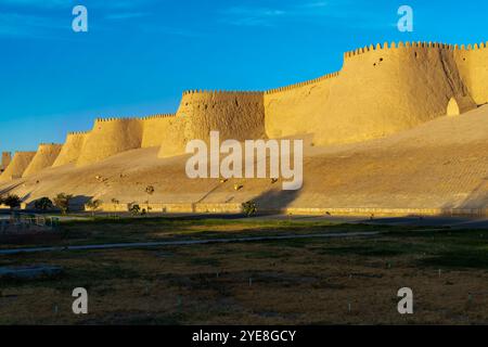 Der Blick auf den Sonnenuntergang auf die zinnenbedeckte Mauer von Chivas Innenstadt, genannt Itchan Kala. Chiwa ist eine Stadt und ein Stadtteil in der Region Chorazm in Usbekistan. Stockfoto