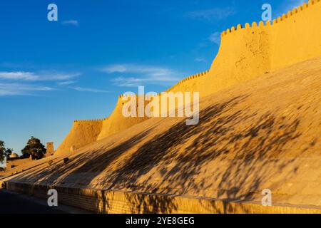 Der Blick auf den Sonnenuntergang auf die zinnenbedeckte Mauer von Chivas Innenstadt, genannt Itchan Kala. Chiwa ist eine Stadt und ein Stadtteil in der Region Chorazm in Usbekistan. Stockfoto