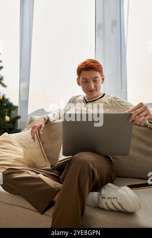 Während der Weihnachtszeit stöbert ein junger Mann gerne auf seinem Laptop, während er sich entspannt. Stockfoto