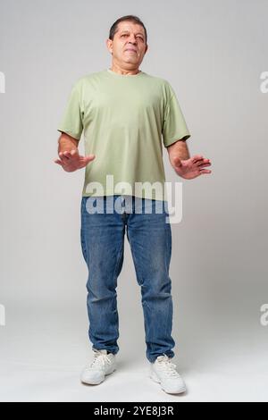 Ein älterer Mann, der selbstbewusst in lässiger Kleidung steht und ein grünes Hemd trägt Stockfoto