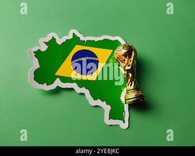 Closeup brasilien Flaggenaufkleber mit Weltmeisterschaft Trophäe auf grünem Hintergrund. Stockfoto