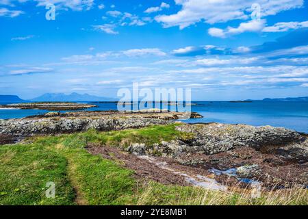 Felsige Küste am Traigh Beach in der Nähe von Portnaluchaig in Lochaber, schottische Highlands, mit Isle of Eigg und Isle of Rum in der Ferne Stockfoto