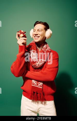 Der junge Mann lächelt fröhlich, während er ein wunderschön gewickeltes Geschenk präsentiert. Stockfoto