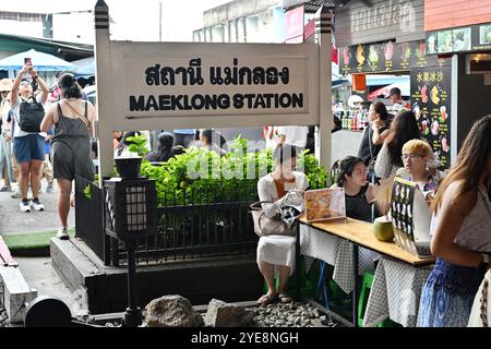 Bahnhofsvorstand Maeklong auf dem Eisenbahnmarkt und Touristen sitzen vor dem Brett Stockfoto
