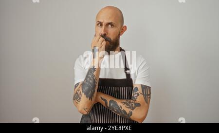 Hispanischer Mann mit Tätowierungen in nachdenklicher Pose isoliert auf weißem Hintergrund Stockfoto